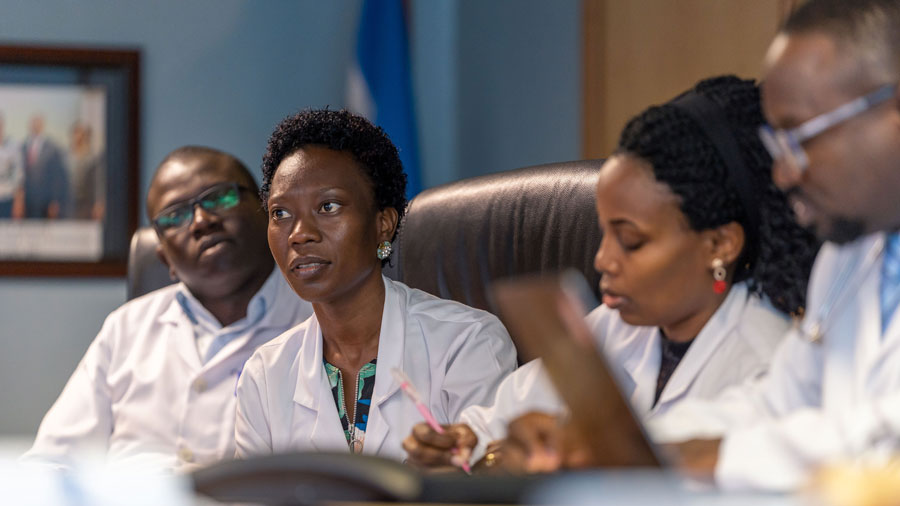 A group of four people in white lab coats engaged in a discussion.